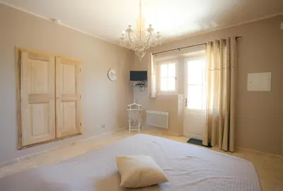 a bedroom with a large white bed with a chandelier at La Collina De Rve in Apt