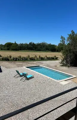 a swimming pool with two chairs on a gravel patio at Charmante maison Provençale avec grand jardin in LʼIsle-sur-la-Sorgue