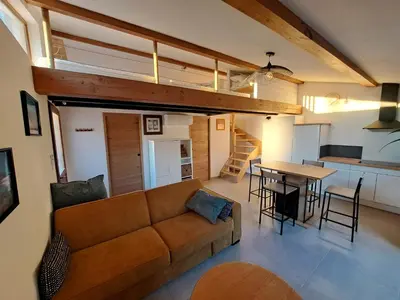 a living room and kitchen with a couch and a table at Gîte Le Dodo in Lançon-Provence