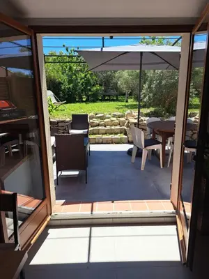 an open door to a patio with a table and an umbrella at Gîte Le Dodo in Lançon-Provence