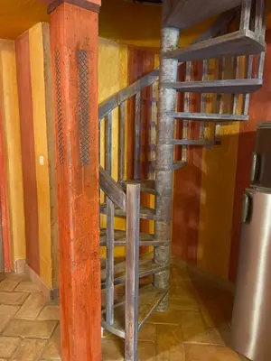 a wooden spiral staircase in a room with a refrigerator at Charmant duplex bucolique, piscine, en Provence in Le Beaucet
