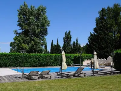 a swimming pool with chairs and umbrellas next to at Charmant duplex bucolique, piscine, en Provence in Le Beaucet