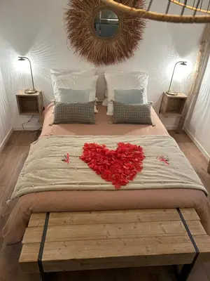a large bed with a heart made out of roses at Cocon cosy appart romantique, jacuzzi piscine in Puget