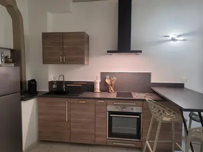 a kitchen with wooden cabinets and a counter top at Appartement Au cœur de l'Isle in LʼIsle-sur-la-Sorgue