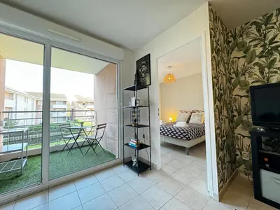 a room with a balcony with a bed and a television at Jungle Cosy - Gare - Bus - Parking gratuit - WIFI in Avignon