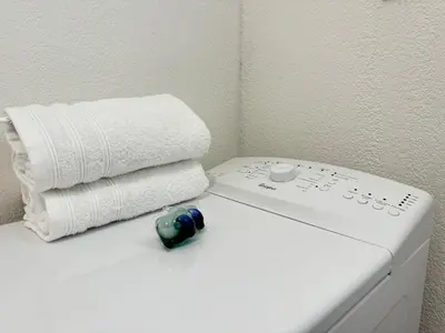 a white bathroom with a stack of towels and a remote control at Jungle Cosy - Gare - Bus - Parking gratuit - WIFI in Avignon