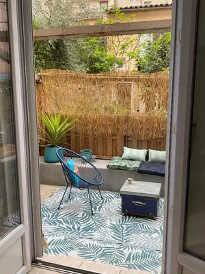 a patio with a blue chair and a couch at Le Petit Vendôme avec terrasse in Aix-en-Provence