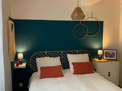 a bed with two red pillows and a blue headboard at Le Petit Vendôme avec terrasse in Aix-en-Provence