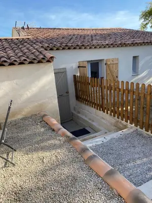 a house with a wooden fence next to a house at Studio à la campagne in La Tour-dʼAigues