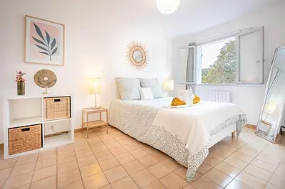 a white bedroom with a bed and a window at Ô Cocon Provençal in LʼIsle-sur-la-Sorgue