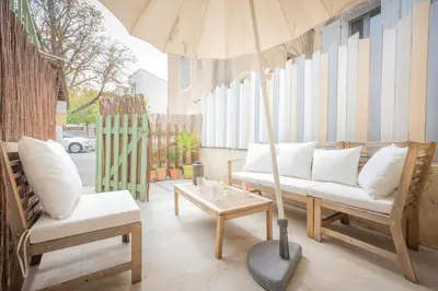 a patio with a couch and a table and an umbrella at Ô Cocon Provençal in LʼIsle-sur-la-Sorgue