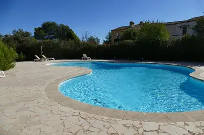 a swimming pool with blue water in a yard at Appartement clim & piscine sur Golf in Pont-Royal en Provence