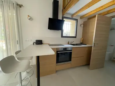 a kitchen with wooden cabinets and a table and a television at STUDIO campagne Les Clapiers AIX EN PROVENCE in Aix-en-Provence