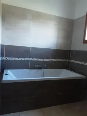 a white bath tub in a bathroom with a wall at Beau mas en campagne de l'Isle sur la Sorgue in LʼIsle-sur-la-Sorgue