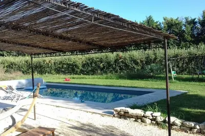 a pergola over a swimming pool in a backyard at Beau mas en campagne de l'Isle sur la Sorgue in LʼIsle-sur-la-Sorgue