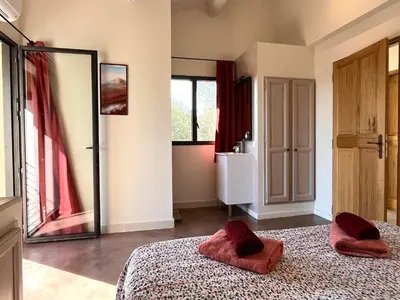 a bedroom with a bed with red pillows and a mirror at La Calade de Goult in Goult