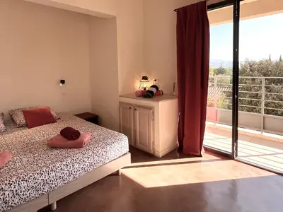 a bedroom with a bed and a window with a balcony at La Calade de Goult in Goult