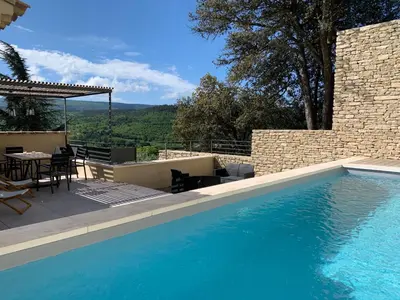 a swimming pool with a table and chairs next to a building at La Calade de Goult in Goult