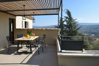a patio with a table and chairs on a balcony at La Calade de Goult in Goult