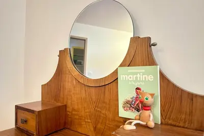a book and a stuffed cat sitting on a table next to a mirror at Comme Chez Mémé house with terrace in the center in Fontaine-de-Vaucluse