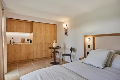 a bedroom with a bed and a table and a kitchen at TERRE UGO - Villa & Suites au cœur des lavandes de Provence in Aix-en-Provence