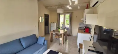 a living room with a blue couch and a kitchen at Restanques de la Tour in La Tour-dʼAigues