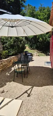 a table and a chair under an umbrella at Restanques de la Tour in La Tour-dʼAigues