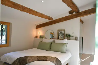 a bedroom with a white bed with green pillows at La Piscine dans la Foret in Gordes