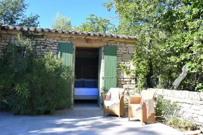 a stone shed with two chairs and a bed at La Piscine dans la Foret in Gordes