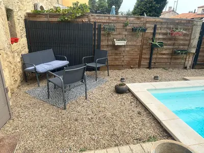 a patio with two chairs and a table next to a swimming pool at Le mazet in Pélissanne