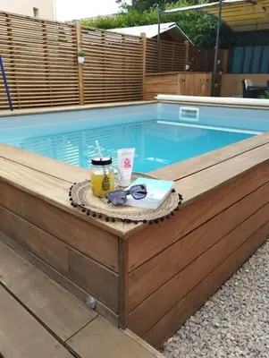a swimming pool with a table with sunglasses and a drink at La Villa Nawengo in Le Thor