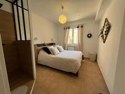 a bedroom with a bed and a large window at La Villa Nawengo in Le Thor