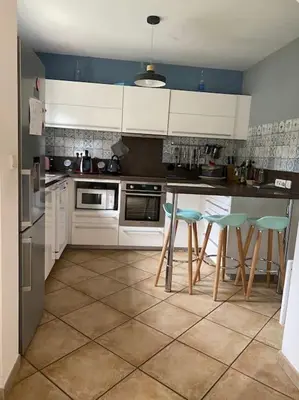 a kitchen with white cabinets and green bar stools at Maison de Vacances en Provence in Venasque