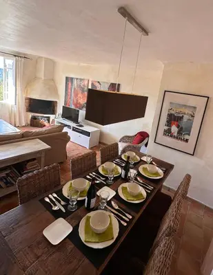 a dining room with a table with chairs and a television at Les 3 Terrasses in Roussillon