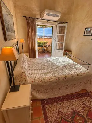 a bedroom with a bed and a table and a window at Les 3 Terrasses in Roussillon