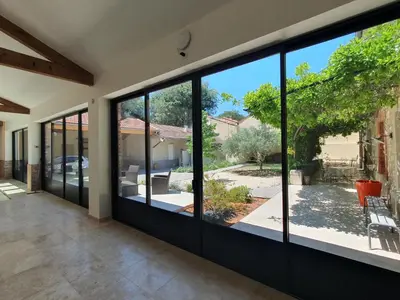 a room with large glass windows in a house at Le grand mas du Couchadou in Pernes-les-Fontaines