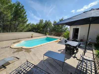 a swimming pool with a table and chairs and an umbrella at Escapade en maisonnette indépendante avec piscine in Châteaurenard