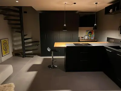 a kitchen with black cabinets and a stair case at L'appart du mas du Zébu Bleu in Vernègues