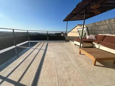 a patio with a couch and an umbrella on a roof at L'appart du mas du Zébu Bleu in Vernègues