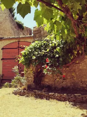 a brick building with a red door and flowers at Maison provençale, piscine, calme et Lubéron in Le Thor