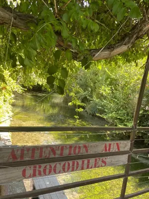 a sign on a fence with a river in the background at Studio5 proche Quai Rouget in LʼIsle-sur-la-Sorgue