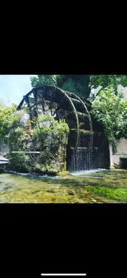 a stone wall with a water fountain in a park at Studio5 proche Quai Rouget in LʼIsle-sur-la-Sorgue