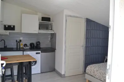 a small kitchen with a table and a door at Studio5 proche Quai Rouget in LʼIsle-sur-la-Sorgue
