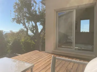 a balcony with a large window on a wooden deck at logement avec jacuzzi in Joucas