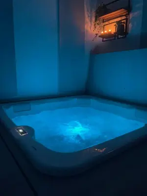 a large blue tub with a light in a room at logement avec jacuzzi in Joucas