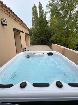 a hot tub on the back of a house at Logis du Vert Moulin Premium in Le Puy-Sainte-Réparade