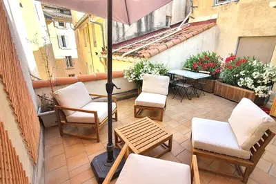 a patio with chairs and a table and an umbrella at Terrasse à Aix en Provence centre historique in Aix-en-Provence