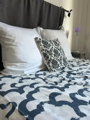 a bed with a black and white comforter and a pillow at Appartement spacieux en Provence in Châteaurenard