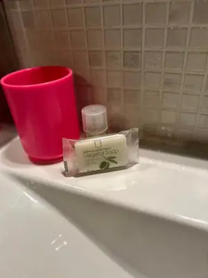 a bottle of soap and a red cup on a sink at Appartement spacieux en Provence in Châteaurenard