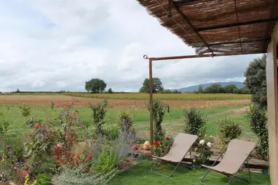 two chairs in a garden with a field in the background at Ferme de restantier, love room in La Tour-dʼAigues